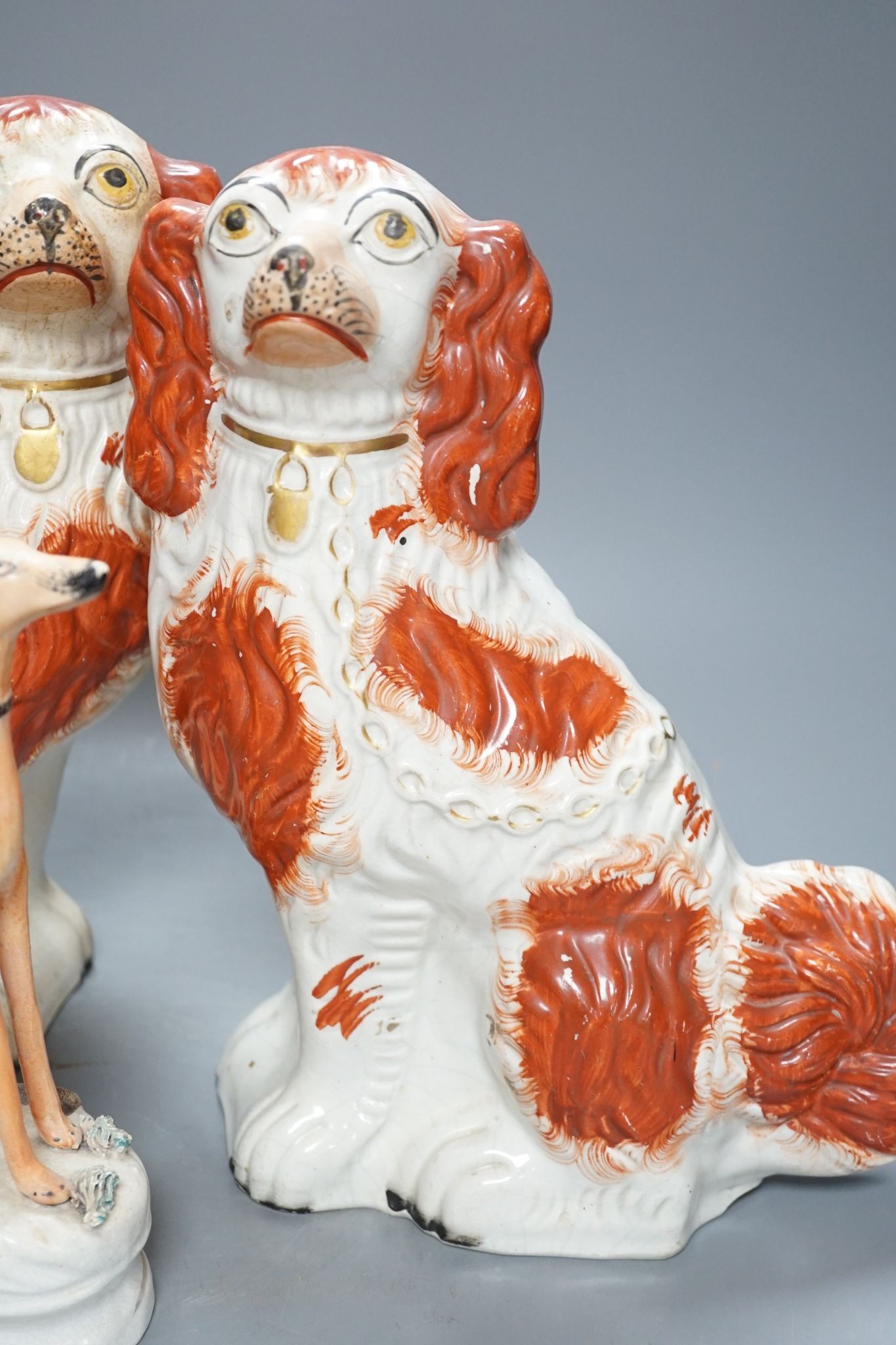 A pair of Victorian Staffordshire Spaniel chimney dogs and a greyhound, chimney dogs 31 cms high.